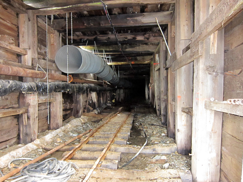Timbered mine entrance with rails and ventilation duct in Wells