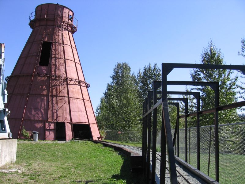 Empty miniature railway track crosses a small bridge beside a beehive burner at Prince George’s railway museum